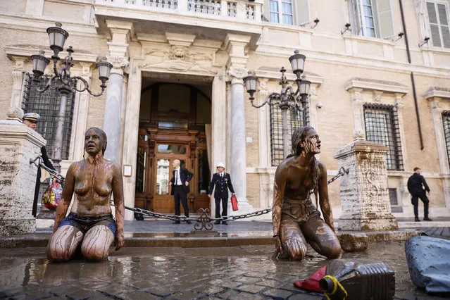 Climate activists of the “Last Generation” covered with mud protest in front of the Senate building in Rome, Italy, Tuesday, May 23, 2023. Two bare breast activists have smeared the facade of the senate with mud, shouting the slogan: “Help us for the ecological transition”. (Photo by Cecilia Fabiano/LaPresse via AP Photo)