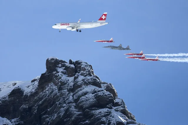 The “Patrouille Suisse” and the Airbus A320 of the Swiss International Airline  perform  during an airshow prior to the men's downhill race at the FIS Alpine Ski World Cup in Wengen, Switzerland, Sunday, January 18, 2015.  (Photo by Peter Klaunzer/AP Photo/Keystone)