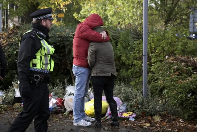 A police officer escorts mourners leaving floral tributes near the scene of an accident where a tram overturned killing 7 people and injuring 50 passengers in Croydon, south London, Britain November 10, 2016. (Photo by Neil Hall/Reuters)