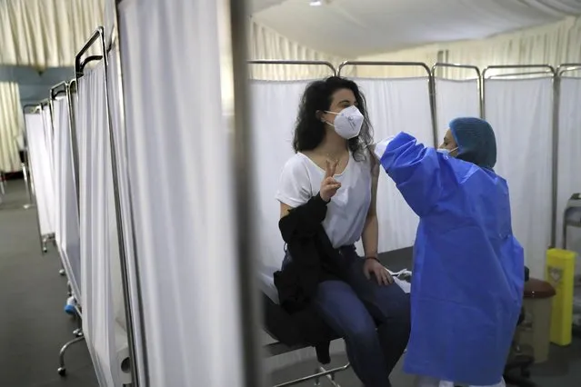 A woman flashes a victory sign as she receives the Pfizer-BioNTech COVID-19 vaccine during a nationwide vaccination campaign, at the Saint George Hospital, in Beirut, Lebanon, Tuesday, February 16, 2021. Lebanon launched its inoculation campaign after receiving the first batch of the vaccine – 28,500 doses from Brussels with more expected to arrive in the coming weeks. (Photo by Hussein Malla/AP Photo)