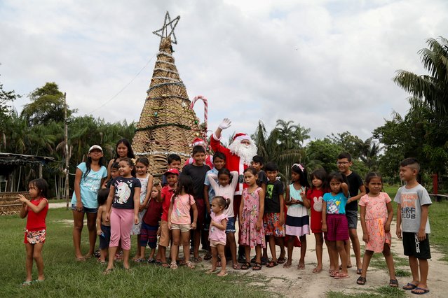 Volunteer Jorge Alberto Barroso, dressed as Santa Claus, poses for a picture with children upon arrival to deliver presents in the riverside community of Abelha, in the city of Manaus, Amazonas State, northern Brazil, on December 20, 2024. Since 1998, the “Friends of Santa Claus” group has been promoting Christmas for children in rural and riverside communities in the Amazon rainforest. (Photo by Michael Dantas/AFP Photo)