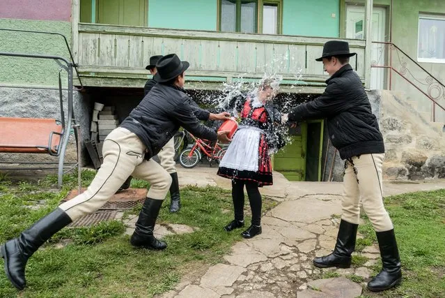 A group of ethnic Hungarian young men dressed in folk costumes pour water on a girl in the Transylvanian village of Csikmindszent, or Misentea in Romanian, Romania, 17 April 2017. According to an old Hungarian tradition, on Easter Monday young men pour water on young women, who in exchange present their sprinklers with hand-decorated hens' eggs. (Photo by Nandor Veres/EPA/EFE)