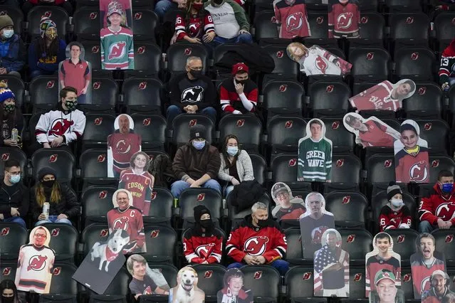 People sit next to cutouts of fans as they watch the first period of an NHL hockey game between the New Jersey Devils and the Buffalo Sabres on Tuesday, March 16, 2021, in Newark, N.J. (Photo by Frank Franklin II/AP Photo)