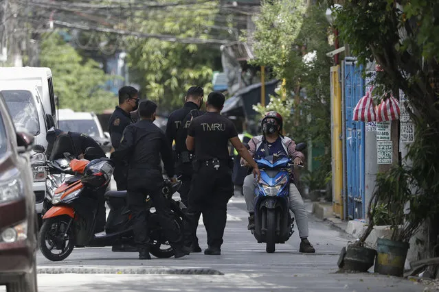 Policemen talk to a resident at a village that was placed under lockdown due to the number of COVID-19 cases among residents in Manila, Philippines on Thursday, March 11, 2021. (Photo by Aaron Favila/AP Photo)