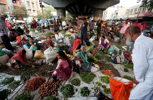 People buy vegetables at a market under a flyover in Ahmedabad, India June 13, 2018. (Photo by Amit Dave/Reuters)
