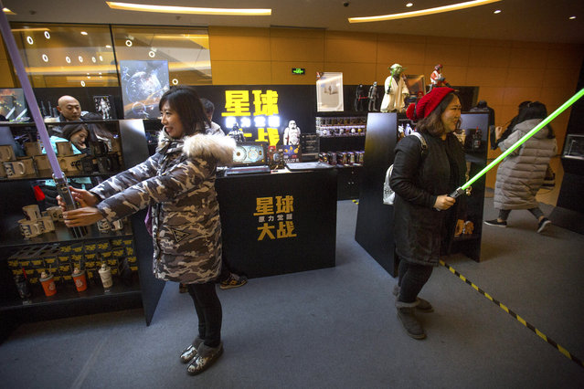 Woman play with lightsabers at a Star Wars merchandise shop at a shopping mall in Beijing, Saturday, January 9, 2016. The record-breaking "Star Wars" opened Saturday in China, where it is far from certain to draw in enough moviegoers to knock off "Avatar" as the world's all-time biggest grossing movie. (Photo by Mark Schiefelbein/AP Photo)