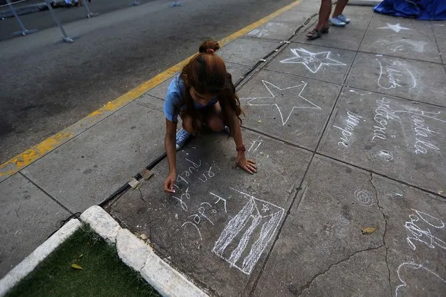A girl writes in chalk a tribute to Fidel Castro in one of the cities where the caravan carrying his ashes will visit in Matanzas, Cuba, November 29, 2016. (Photo by Ivan Alvarado/Reuters)