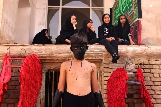 A youth waits for the face paint to dry up in preparation for the annual religious performance of Taazieh in the Iranian city of Noosh Abad on July 26, 2023, during the Muslim month of Muharram in the lead-up to Ashura, a 10-day period commemorating the seventh century killing of Prophet Mohammed's grandson Imam Hussein. (Photo by Atta Kenare/AFP Photo)