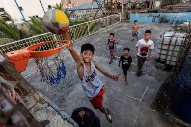 Children play basketball on the rooftop of tenement housing in Tondo, Manila, Philippines on May 17, 2023. Basketball is played everywhere and by almost everyone in the Philippines, which counts the sport as a national obsession along with boxing and beauty pageants. Enthusiasm for the sport is only intensifying ahead of the 2023 FIBA Basketball World Cup, which opens in Manila on Friday. (Photo by Eloisa Lopez/Reuters)