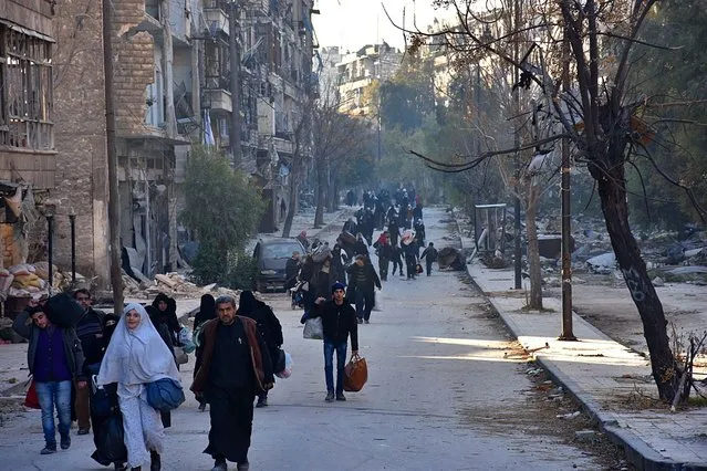 Syrian residents fleeing the violence in the eastern rebel- held parts of Aleppo evacuate from their neighbourhoods through the Bab al- Hadid district after it was seized by the government forces, on December 7, 2016. In the face of a blistering assault by forces loyal to President Bashar al- Assad, the rebels were reported to have retreated from all of Aleppo' s Old City, the latest in a string of territorial losses. (Photo by George Ourfalian/AFP Photo)