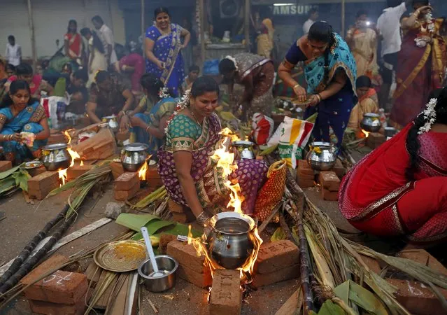 A devotees lights fire as she prepares ritual rice dish to offer to the Hindu Sun God as they attend Pongal celebrations at a slum in Mumbai, India, January 15, 2016. (Photo by Danish Siddiqui/Reuters)