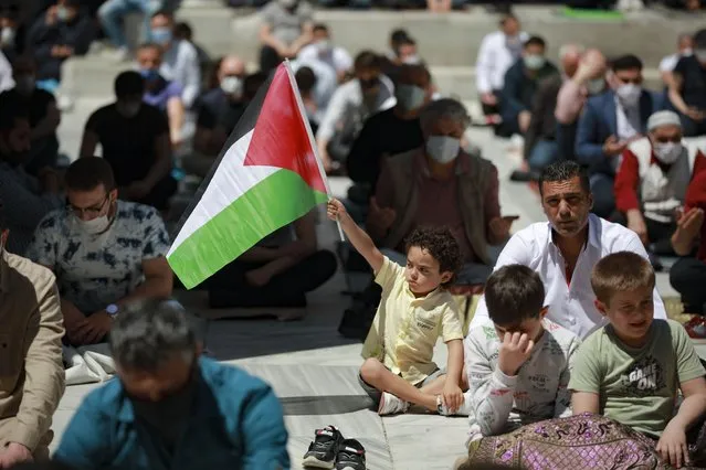 A child holds a Palestinian flag during Friday prayers outside Fatih mosque in Istanbul, Friday, May 4, 202. People in Turkey have been demonstrating this week against Israel and in support of Palestinians, killed in the recent escalation of violence in Jerusalem and the Gaza Strip, without much interference from the police despite a strict lockdown to curb COVID-19 infections that have ordered people to stay home until May 17. (Photo by Emrah Gurel/AP Photo)