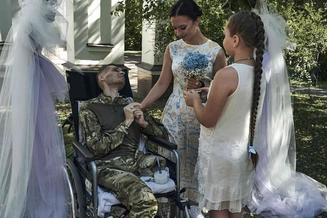 Topolnitsky Vlad, 26, a soldier who was badly wounded in a battle with the Russian troops, and his wife Hanna, 22, share a tender moment during their wedding ceremony in hospital in Kyiv, Ukraine, Thursday, September 7, 2023. (Photo by Libkos/AP Photo)