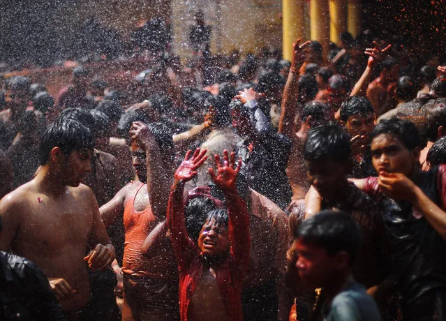 A boy is daubed in colours as he stands under a shower during “Huranga” at Dauji temple, near the northern Indian city of Mathura, March 7, 2015. (Photo by Adnan Abidi/Reuters)
