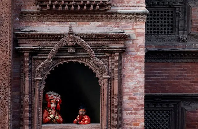 Young girls dressed as the Living Goddess Kumari look through the window of a temple as they pose for a photograph during the Kumari Puja, in which young girls pose as the Living Goddess Kumari and are worshipped by people in the belief that their children will remain healthy, in Kathmandu, Nepal on September 27, 2023. (Photo by Navesh Chitrakar/Reuters)
