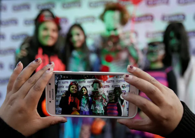 A woman takes a picture of people in costume during Halloween celebrations in La Paz, Bolivia on October 31, 2018. (Photo by David Mercado/Reuters)
