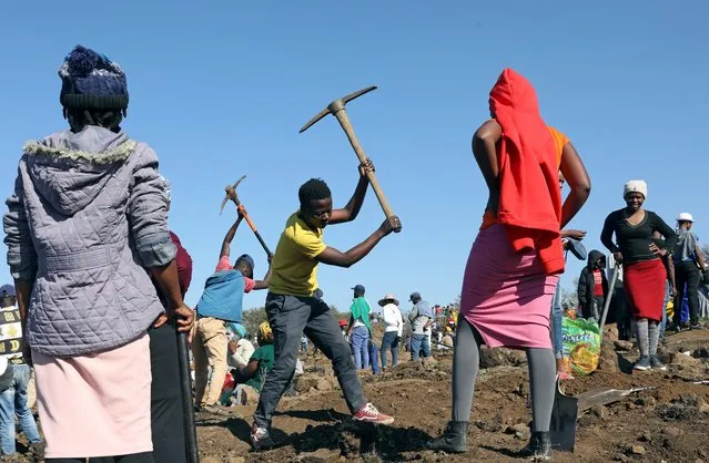 A man uses a pickaxe to dig as fortune seekers flock to the village after pictures and videos were shared on social media showing people celebrating after finding what they believe to be diamonds, in the village of KwaHlathi outside Ladysmith, in KwaZulu-Natal province, South Africa, June 14, 2021. (Photo by Siphiwe Sibeko/Reuters)
