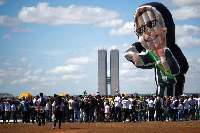 Demonstrators inflate a doll depicting Brazil's President Jair Bolsonaro during a protest in support of gun rights and Brazilian President Jair Bolsonaro, in Brasilia, Brazil, July 9, 2022. (Photo by Adriano Machado/Reuters)
