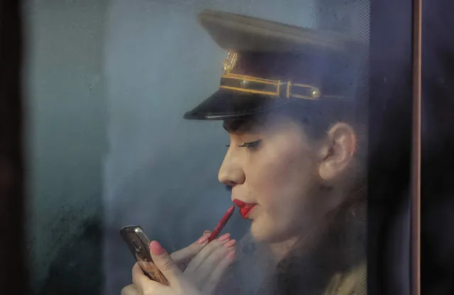 A Romanian military medical student applies lipstick before taking part in Romania's National Day parade in Bucharest, Romania, Thursday, December 1, 2016. Military planes and helicopters flew over the Romanian capital Thursday as thousands turned out to celebrate the national day, marking the date when the country reunified with Transylvania in 1918. (Photo by Vadim Ghirda/AP Photo)