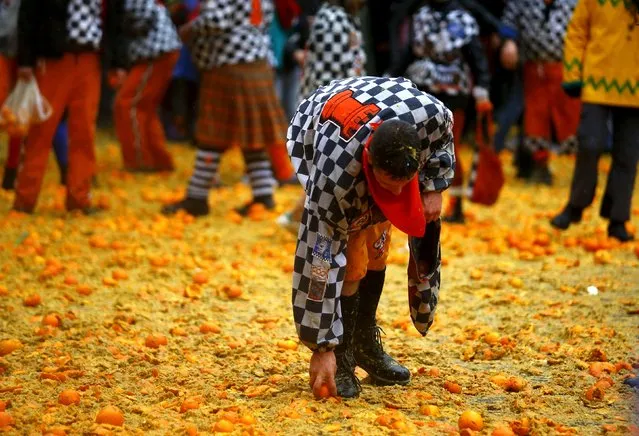 A member of a rival team collects a orange from the ground during an annual carnival battle in the northern Italian town of Ivrea February 7, 2016. (Photo by Stefano Rellandini/Reuters)