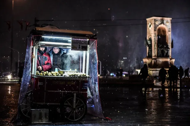 Street vendors sell chestnuts under the snow at Taksim Square in Istanbul on December 16, 2016. (Photo by Yasin Akgul/AFP Photo)