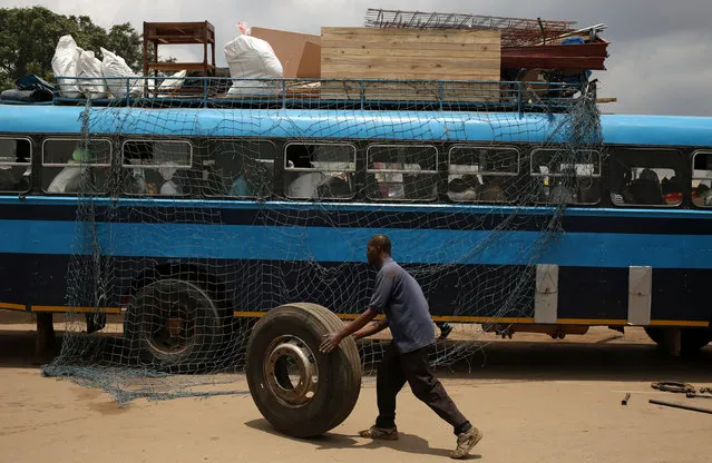 A man pushes a wheel after changing a tyre ahead of a long distance trip at a bus terminus in Mbare township, outside Harare, Zimbabwe, November 27, 2017. (Photo by Siphiwe Sibeko/Reuters)