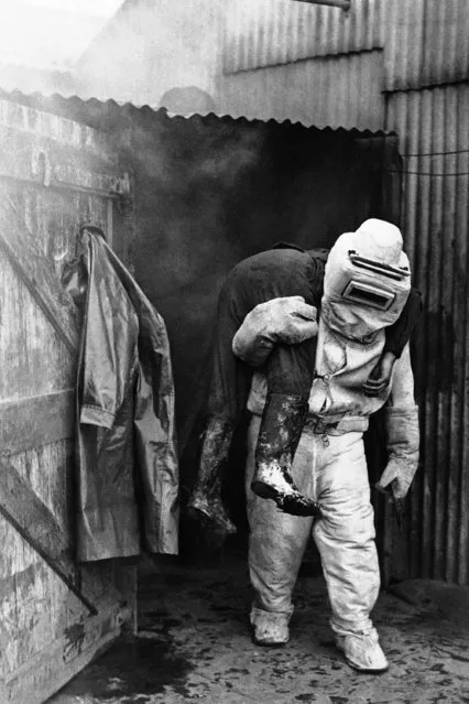 Rehearsing somewhere in England, an asbestos-suited soldier carries a victim from a burning shed, October 24, 1941. Soldiers are being trained for air raid precautions work in bombed areas. (Photo by AP Photo)