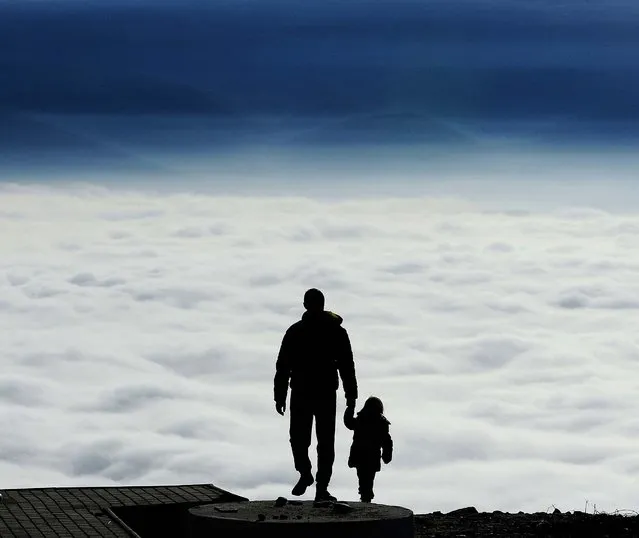 A man with a child walks towards the top of Vodno Mountain in Skopje, Macedonia, on January 9, 2014. (Photo by Boris Grdanoski/Associated Press)