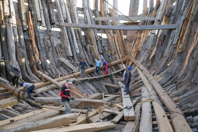A crew works on a traditional ship under construction in Mandvi in Gujarat, India, Tuesday, January 9, 2024. This 400-year-old tradition of shipbuilding using manual tools is in decline but a few ships are still built each year to be used for fishing and transporting goods. (Photo by Ashwini Bhatia/AP Photo)