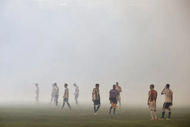 Red Star Belgrade and Partizan Belgrade players stand on the pitch amidst smoke during their Serbian Superliga soccer match in Belgrade, April 25, 2015. (Photo by Marko Djurica/Reuters)