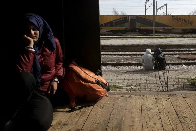 A migrant (L) finds shelter in a train wagon as others sit near the railway tracks at the Greek-Macedonian border, near the village of Idomeni, Greece March 6, 2016. (Photo by Alexandros Avramidis/Reuters)