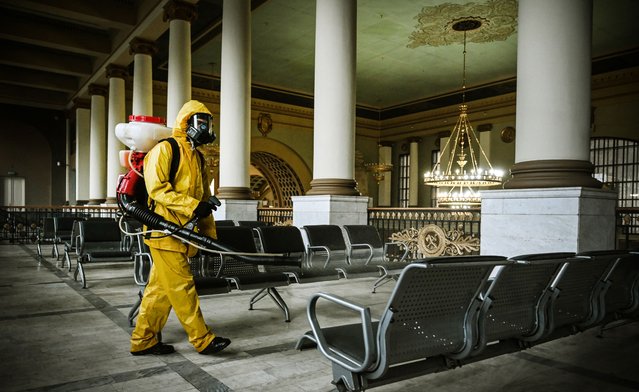 A serviceman of Russia's Emergencies Ministry, wearing protective gear, disinfects Kievsky railway terminal amid the COVID-19 pandemic in Moscow on September 22, 2021. (Photo by Alexander Nemenov/AFP Photo)
