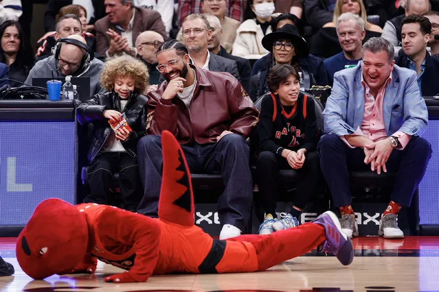 Canadian rapper Drake and his son Adonis Graham watch as the Raptors mascot goofs around in front of them during a timeout in the first half of the NBA game between the Toronto Raptors and the Los Angeles Lakers at Scotiabank Arena on December 7, 2022 in Toronto, Canada. (Photo by Cole Burston/Getty Images)