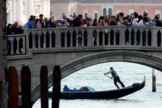 Tourists walk on a bridge as a gondolier rows his gondola near St.Marks Square in Venice, Italy, April 2, 2019. (Photo by Guglielmo Mangiapane/Reuters)