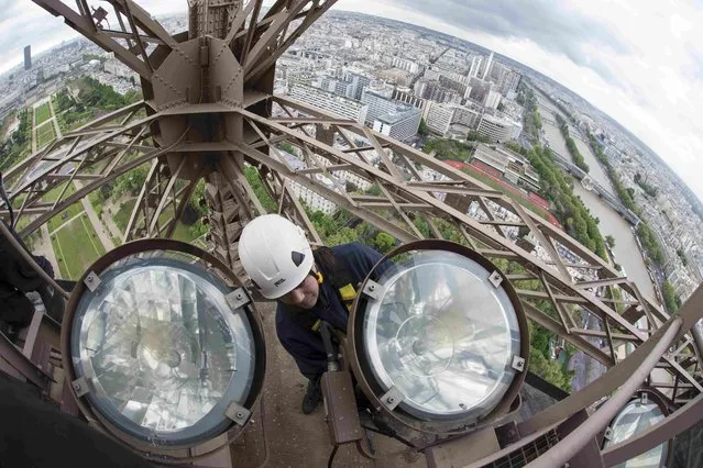 Technician Pascal Duteil changes one of the sodium golden light bulbs on the Eiffel tower in Paris, France, May 5, 2015. A campaign to change and clean the 425 golden light bulbs starts today and is done every four years. (Photo by Philippe Wojazer/Reuters)
