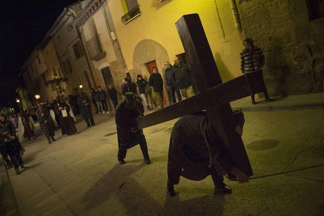 Masked penitents carrying a cross as they take part in the procession of the “Ensogado”, during Holy Week in Sietamo, northern Spain, Thursday, March 24, 2016. (Photo by Alvaro Barrientos/AP Photo)