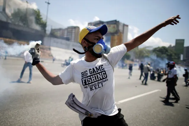 An opposition demonstrator throws back a tear gas canister on a street near the Generalisimo Francisco de Miranda Airbase “La Carlota”, in Caracas, Venezuela April 30, 2019. (Photo by Ueslei Marcelino/Reuters)