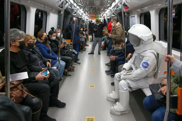 A man dressed as an astronaut takes a ride in metro as part of a campaign to promote a NASA Space Exhibition in Istanbul, Turkey, Saturday, December 4, 2021. (Photo by Emrah Gurel/AP Photo)