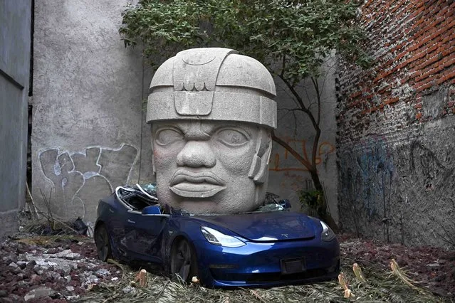 An artwork by artist Chavis Marmol, a Tesla 3 car crushed by a nine-ton Olmec-inspired head, is pictured in Mexico City on March 13, 2024. (Photo by Carl de Souza/AFP Photo)