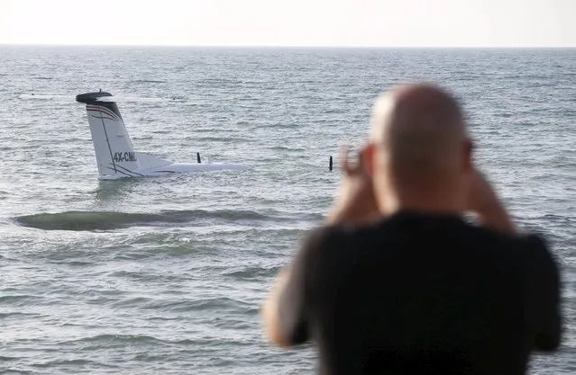 A man takes a photo with his cell phone of an airplane that made an emergency landing in the waters of the Mediterranean sea off the shore of Tel Aviv, Israel, April 3, 2016. (Photo by Baz Ratner/Reuters)