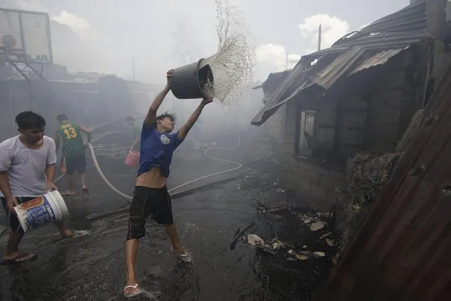 Filipino residents douse pails of water to help fight a fire which left at least 60 families homeless at a slum area in suburban Quezon city, north of Manila, Philippines, Friday, April 8, 2016. Firefighting forces go on the highest alert during the hot summer months when fire breaks out often nationwide. (Photo by Aaron Favila/AP Photo)