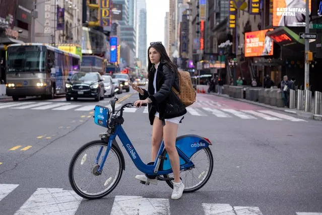 A woman rides a bicycle in her shorts during a warm day through Times Square in the Manhattan borough of New York City, New York, U.S., December 16, 2021. (Photo by Jeenah Moon/Reuters)