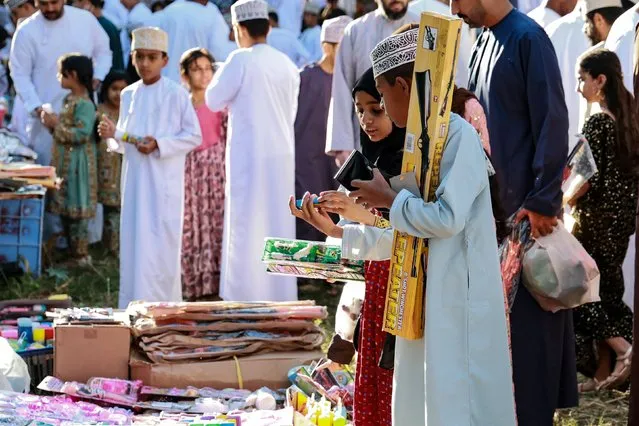 Children choose gifts at a market, as Muslims prepare to celebrate the Eid al-Fitr holiday marking the end of Islam's holy fasting month of Ramadan, in the Sarur area of Oman's Samail governorate on April 6, 2024. (Photo by Haitham Al-Shukairi/AFP Photo)