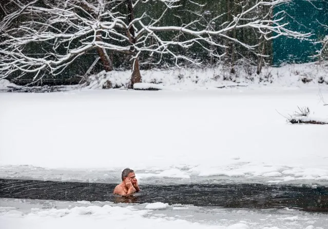 A man swims in the ice cold water of the Bottomless Lake in Serebryany Bor, in Moscow, Russia, Sunday, December 5, 2021. Moscow temperatures on Sunday dropped to –5 C ( 23 F). (Photo by Alexander Zemlianichenko/AP Photo)