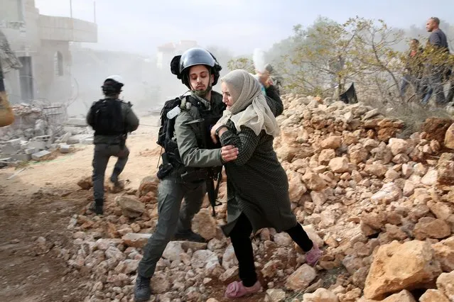 Palestinian women clash with Israeli soldiers as they react against the demolishing of their under-construction house, in the West Bank city of Hebron, 28 December 2021. According to Israeli authorities, the construction was built without obtaining necessary permits. (Photo by Abed Al Hashlamoun/EPA/EFE)