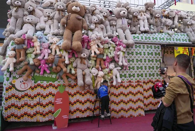 A man takes a photo of a child in front of a teddy bear collection near a shopping mall in Beijing, China, Friday, April 5, 2024. (Photo by Tatan Syuflana/AP Photo)