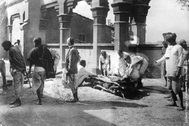 1910: A group of men laying a body on a Hindu ghat, which serves as a place of cremation
