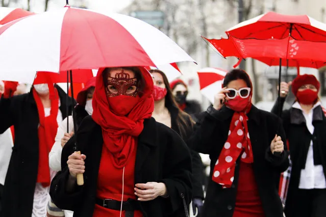 Women march down the streets under umbrellas in the colours of the former white-red-white flag of Belarus to protest against the Belarus presidential election results in Minsk, on March 11, 2021. Belarus has been gripped by months of unprecedented anti-government demonstrations that erupted after a disputed presidential election last August 2020 which saw Belarus's strongman leader Alexander Lukashenko claim a sixth term in office. (Photo by AFP Photo/Stringer)