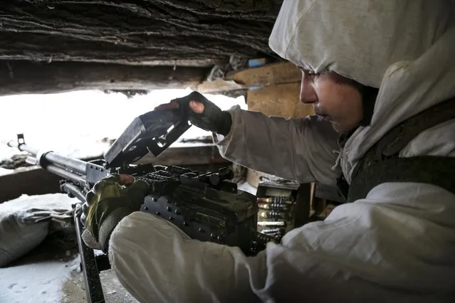 A serviceman checks his machine-gun in a shelter on the territory controlled by pro-Russian militants at frontline with Ukrainian government forces in Slavyanoserbsk, Luhansk region, eastern Ukraine, Tuesday, January 25, 2022. Ukraine's leaders sought to reassure the nation that a feared invasion from neighboring Russia was not imminent, even as they acknowledged the threat is real and prepared to accept a shipment of American military equipment Tuesday to shore up their defenses. (Photo by Alexei Alexandrov/AP Photo)