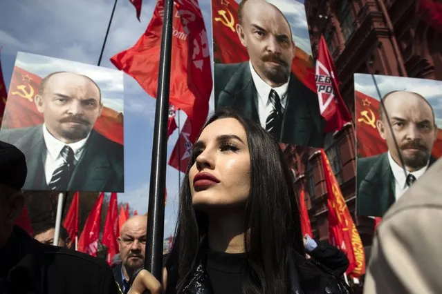 Russian communist supporters hold their flags and portraits of Vladimir Lenin as they walk to visit the Mausoleum of the Soviet founder Vladimir Lenin to mark the 151st anniversary of his birth, in Moscow, Russia, Thursday, April 22, 2021. (Photo by Pavel Golovkin/AP Photo)